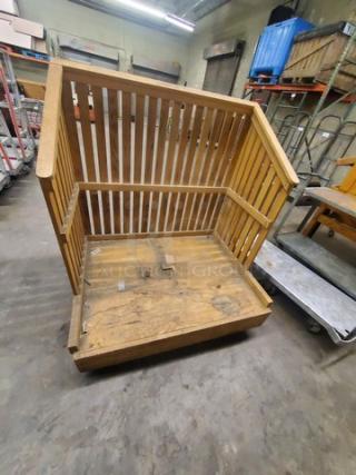 Wooden utility cart with slatted sides and a flat base, showing signs of wear. Ideal for storage or transport purposes.