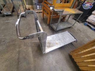 Metal utility cart with a sturdy handle and wheeled base. Appears used, with visible wear and scratches. Suitable for transport tasks.
