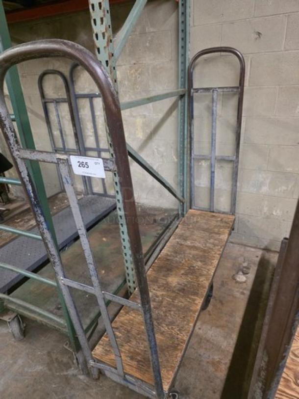 Weathered stock cart with metal frame and wooden base. Includes wheels for mobility. Label marked "265". Ideal for warehouse use.