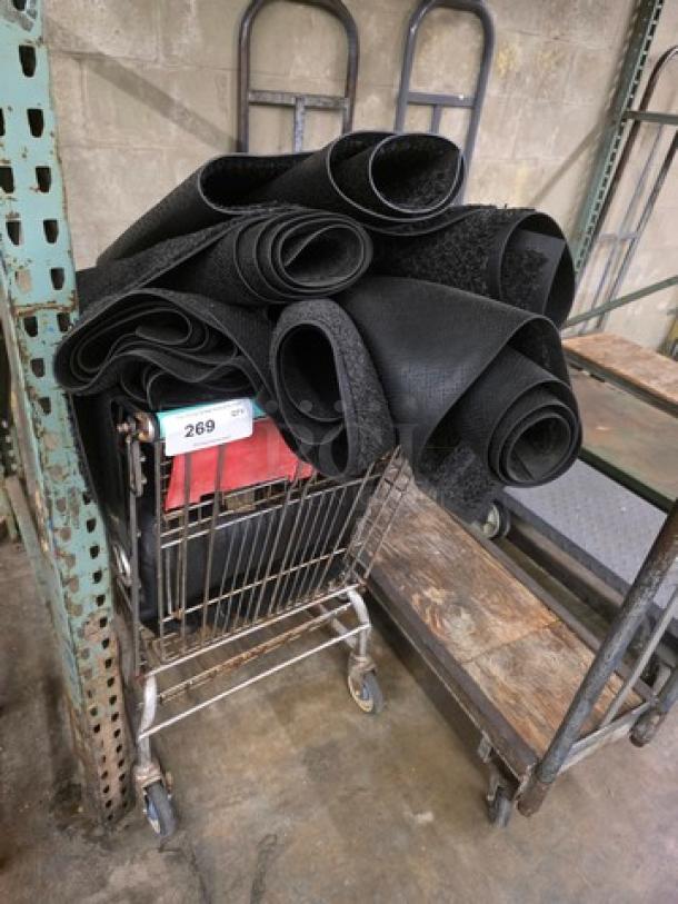 Shopping cart filled with rolled black rugs, item tag labeled "269," in warehouse setting.