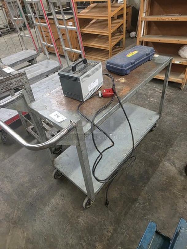 Steel utility cart with two shelves and wheels in used condition. Contents on cart not included.