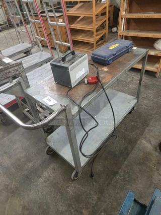 Steel utility cart with two shelves and wheels in used condition. Contents on cart not included.