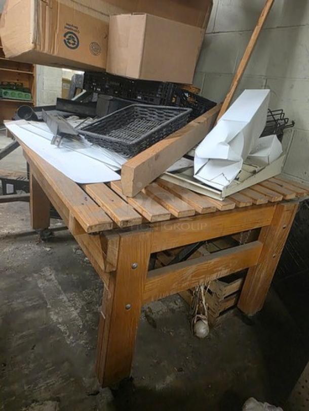 Wooden workbench with slatted top, natural finish. Includes additional items on surface. Used condition.