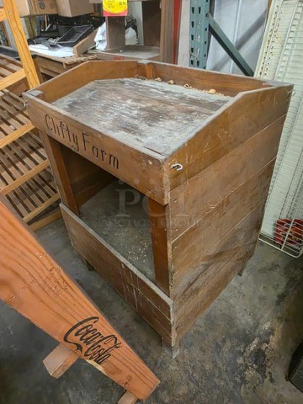 Wooden display bin with "Clifty Farm" engraving, rustic condition, featuring open storage space. Suitable for farm or rustic decor.