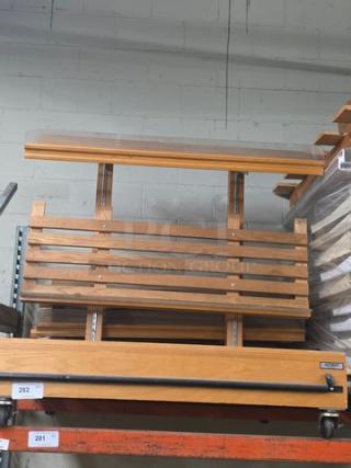 Wooden bench with slatted backrest and seat, sturdy construction, natural finish, mounted on wheeled platform, good condition.