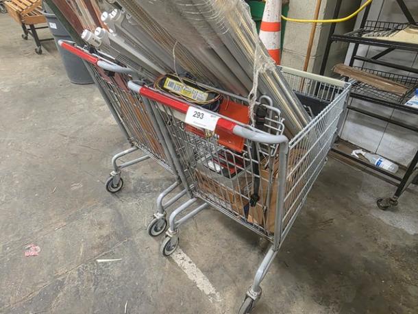 Two metal shopping carts, slightly used, with red handles, holding various items. Label "293" visible on cart.
