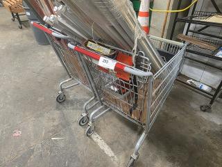 Two metal shopping carts, slightly used, with red handles, holding various items. Label "293" visible on cart.