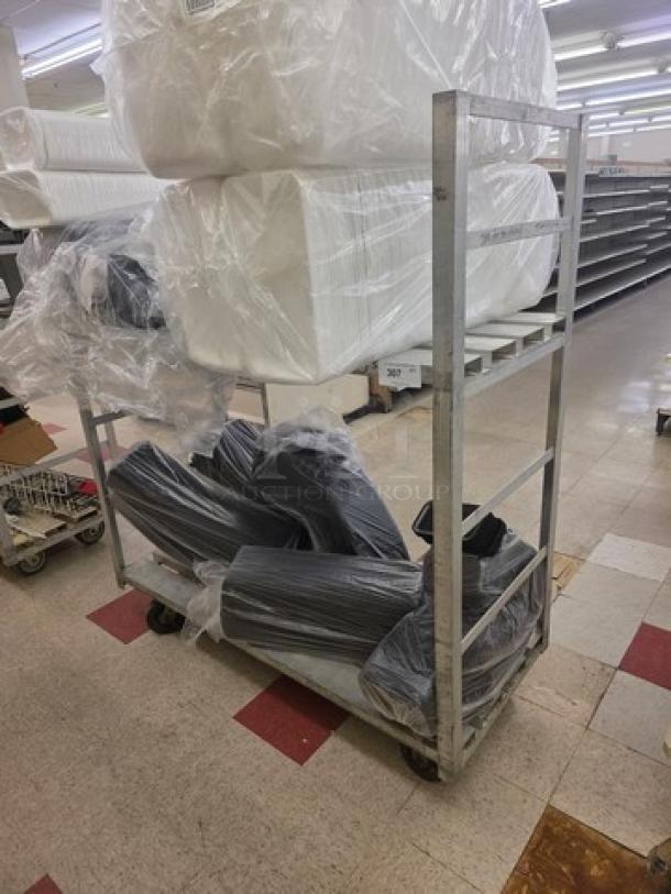 Aluminum mobile cart with four wheels, open shelves, and a sturdy frame. Signs of use visible; contents not included.