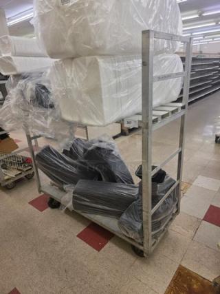 Aluminum mobile cart with four wheels, open shelves, and a sturdy frame. Signs of use visible; contents not included.