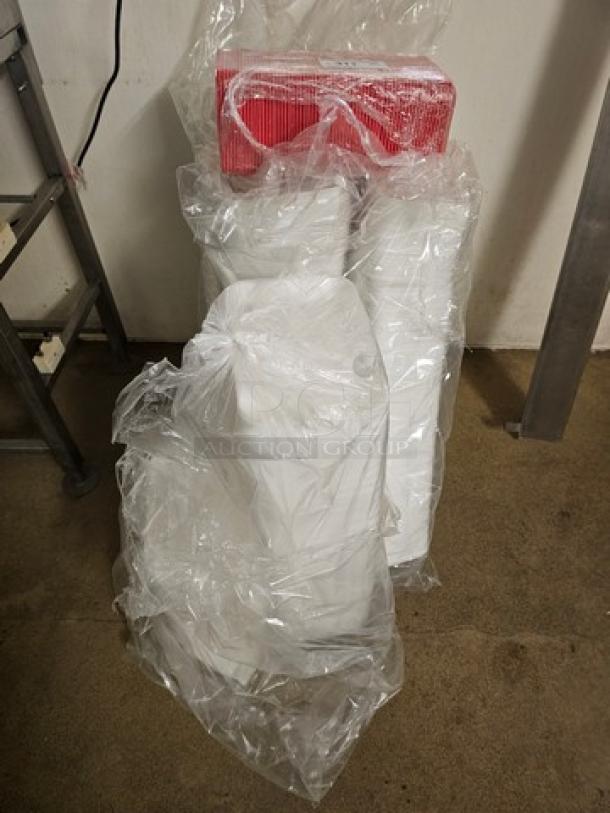 Bulk disposable food trays covered in clear plastic wrap, new condition, stacked with red packaging detail visible.