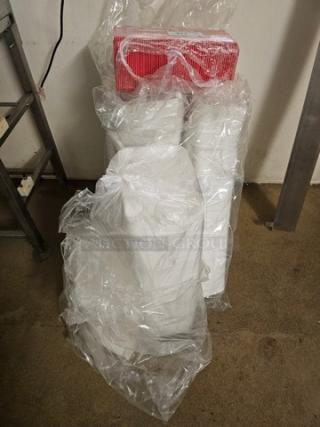 Bulk disposable food trays covered in clear plastic wrap, new condition, stacked with red packaging detail visible.