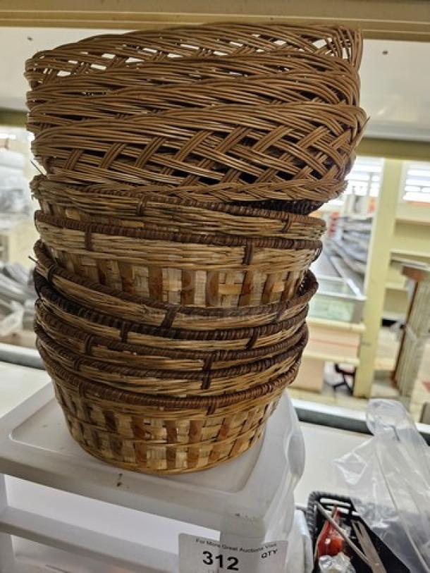 Stack of wicker baskets, varying weaves and sizes, on a shelf. Tag shows auction item number 312 in good condition.