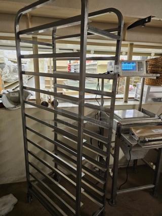 Stainless steel sheet pan rack with multiple shelves, on casters for mobility. Used condition, ideal for baking storage.