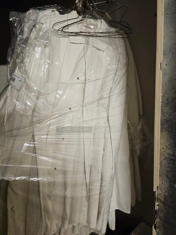 Lot of white butchers coats on hangers, plastic-wrapped, in good condition. Ideal for professional use.