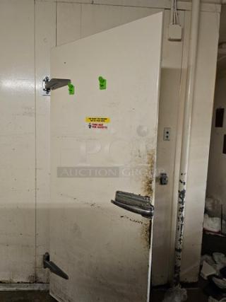 White walk-in door with attached hinges and handles, showing wear and some rust. Includes hardware and safety sticker.