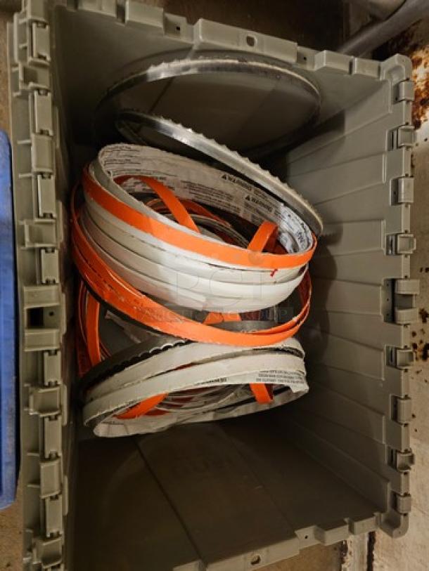 Lot of band saw blades in a gray storage bin, featuring various sizes and colors, appears used with visible wear.