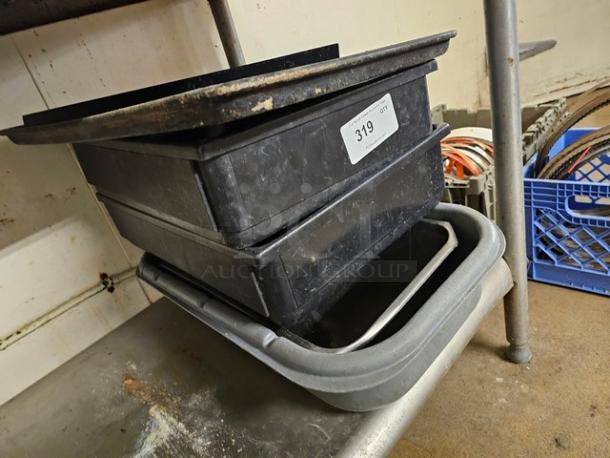 Lot of miscellaneous kitchenware including stacked black trays and a gray container, used condition. Auction tag 319 visible.