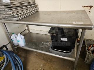 Stainless steel work table with lower shelf, durable construction, moderate wear, ideal for kitchen or industrial use. Contents not included.