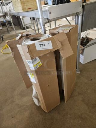 Rolls of plastic sheeting in partially opened cardboard box, showing labels with quantity and barcodes, in fair condition.