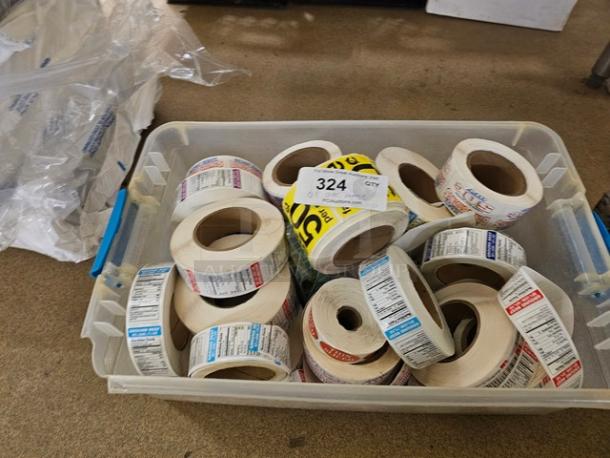 Plastic bin with assorted label rolls, various colors and prints. Lot number 324 visible on top. Ideal for organization.