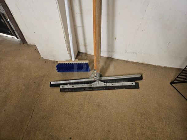 Lot of 3 miscellaneous push brooms on a beige floor; includes metal and wood handles, blue bristles, used condition.