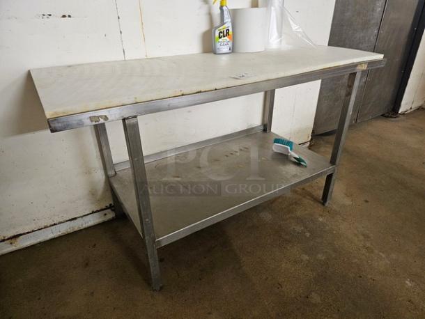 Industrial butcher block table with a white cutting surface, stainless steel legs, and lower shelf. Used condition.