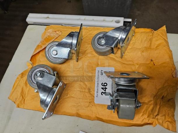 Lot of four metal casters on a yellow envelope. Each caster has a swivel mechanism. Visible tag reads "346 QTY."