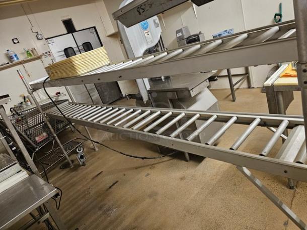 Stainless steel roller conveyor system in industrial setting. Good condition. Buyer handles removal. Includes multiple rollers.