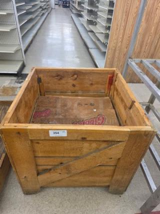 Wooden display bin with sturdy construction, featuring visible worn finish, cross-brace design, and labels on interior.