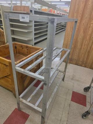 Metal dunnage rack, rectangular frame, sturdy bars, used for storage and organization. Metal finish, number 355 tag visible.
