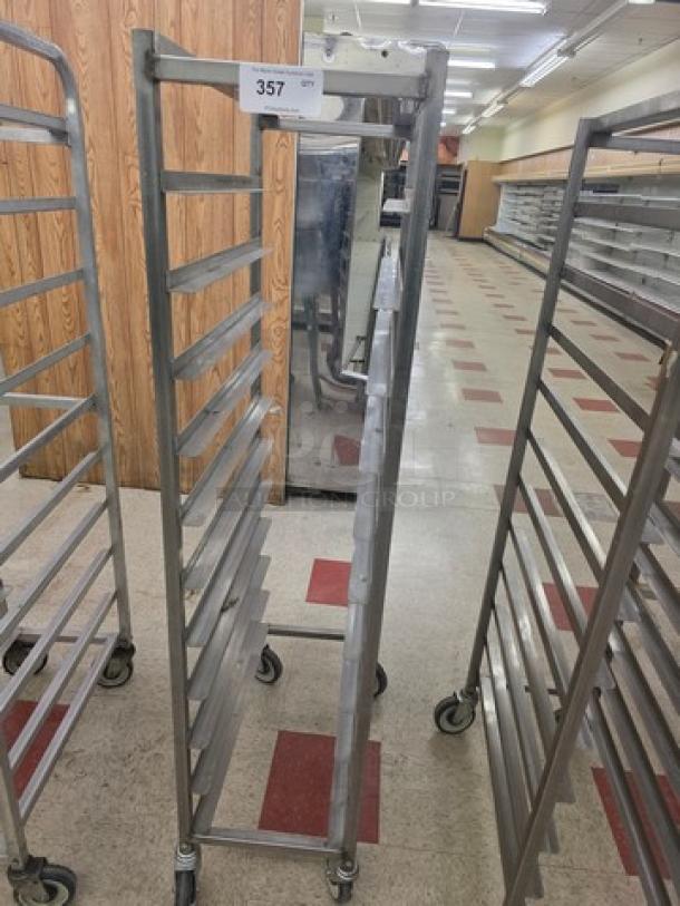 Stainless steel mobile sheet pan rack with multiple slots, caster wheels, and a tag labeled "357." Suitable for bakery use.