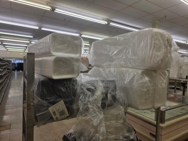 Stacks of disposable food trays in clear plastic wrap on metal shelving in a warehouse.