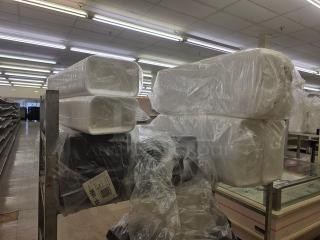 Stacks of disposable food trays in clear plastic wrap on metal shelving in a warehouse.