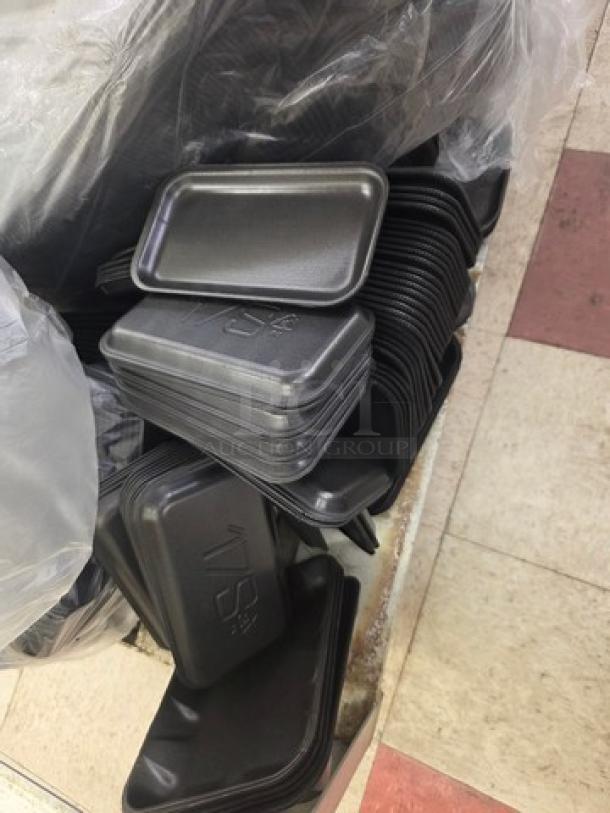 Stack of black disposable food trays in new condition, showing recyclable material symbol on each tray.