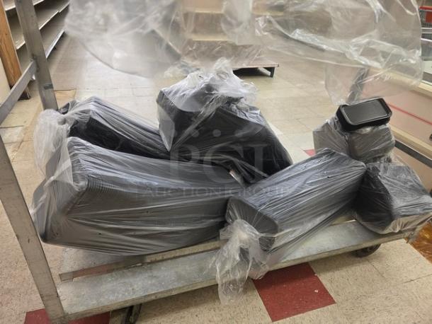 Plastic-wrapped lot of black disposable food trays on metal cart, stacked and ready for use or resale.