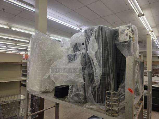 Lot of disposable food trays wrapped in plastic, stacked on metal shelving. Includes white and black trays. Tags visible.