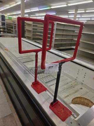 Lot of two red metal sign holders, square frames, with adjustable black stands. Each holder features a mounting base.