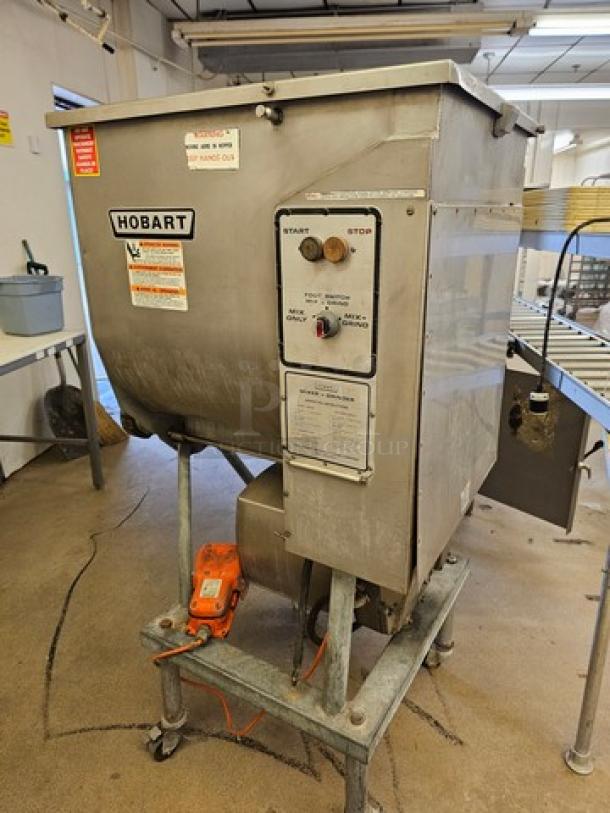 Hobart Meat Grinder & Mixer, stainless steel, industrial size, control panel with start/stop buttons, mounted on a metal stand.
