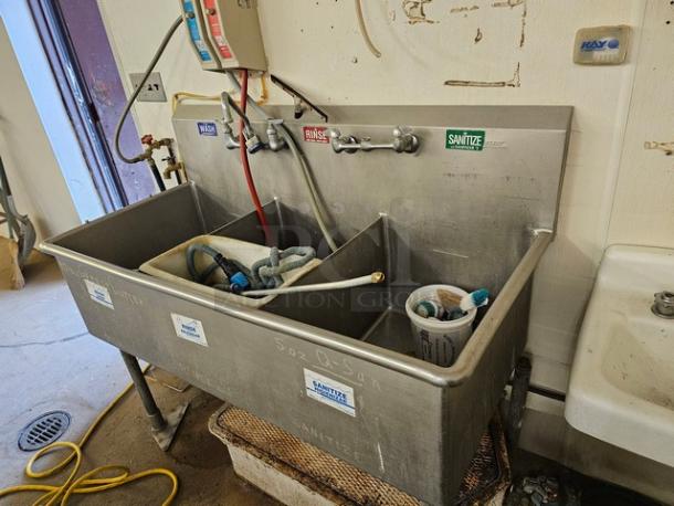Commercial stainless steel 3 compartment sink with labeled wash, rinse, and sanitize taps, good condition, visible plumbing.