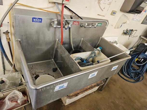 Stainless steel 3 compartment sink with labeled wash, rinse, sanitize sections; visible wear and hoses included.