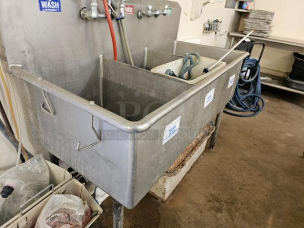 Stainless steel 3 compartment sink with faucets and handles. Labels indicate wash, rinse, sanitize. Used condition.