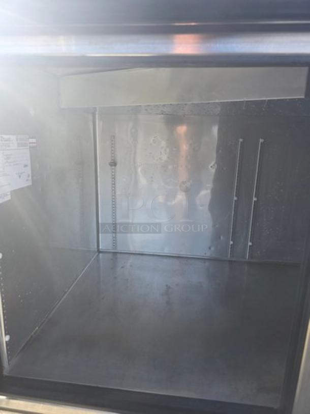 True 2 Door Pizza Prep Table TPP-67 interior showing stainless steel surface and shelving rails. Good condition. Model label visible.
