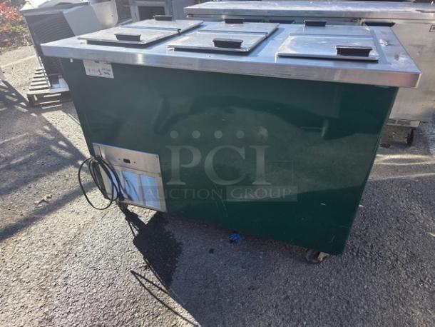 Delfield model KCF-50 ice cream counter, green, three covered compartments, mobile with wheels, exterior wear visible.