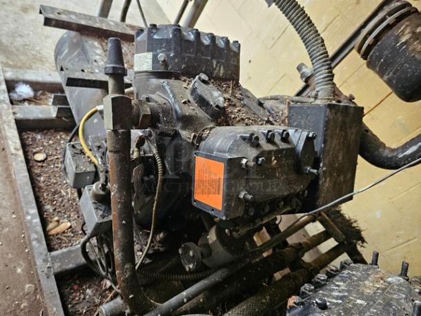 Commercial refrigeration compressor rack, medium temp 404A, 40 HP, shows wear and rust. Orange label on the unit.