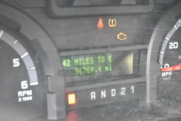 Dashboard of 2012 Ford E-350 Van showing odometer reading 96,764 miles, fuel gauge, and warning lights.