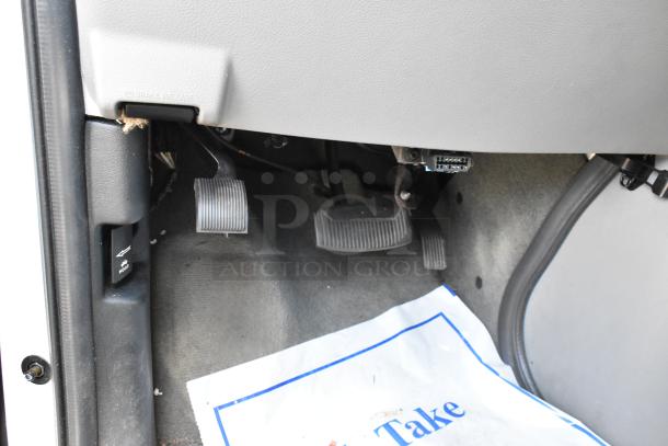 Interior view of 2012 Ford E-350 Van dashboard and pedals, showing hood release lever. Odometer reads 96,764. VIN 1FBSS3BL3CDA01043.