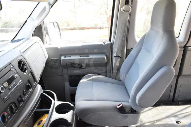 2012 Ford E-350 Van interior, front passenger seat view, showing dashboard and seatbelt. Dashboard features standard controls.