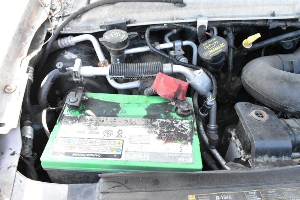 Engine bay of a 2012 Ford E-350 Van showing the battery compartment and various engine components.