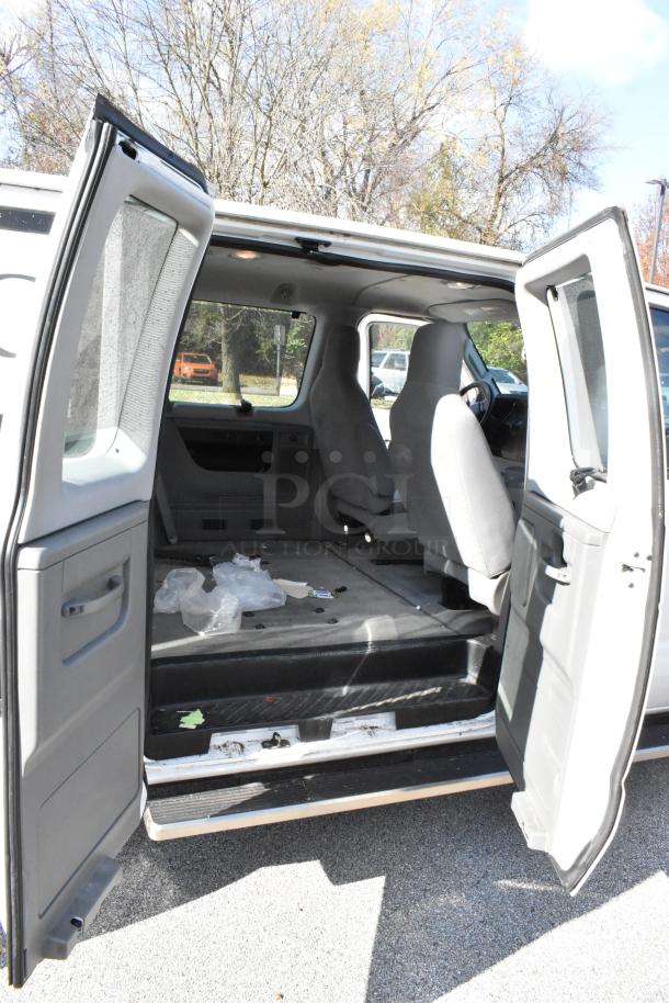 2012 Ford E-350 Van interior, with four removable back seats. Odometer reads 96,764. Open doors show spacious cabin. VIN visible.