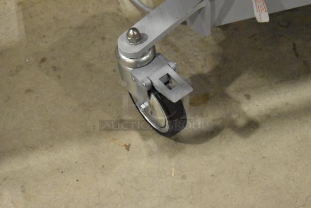 Northeast Medical Systems portable hospital bed caster, showing commercial wheel and brake mechanism on concrete floor.